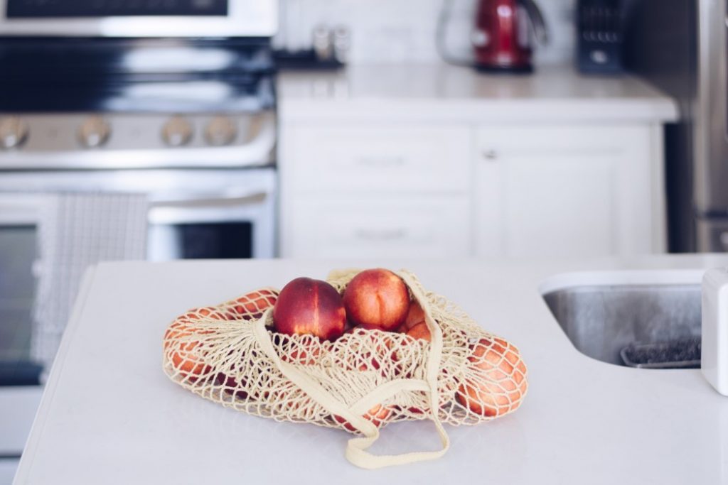 a reusable produce bag with peaches in it on a kitchen countertop